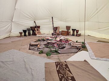 Ein Blick ins Tipi mit Feuerstelle und Musikinstrumenten